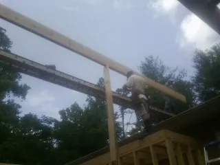 Carpenter setting a ridge beam over a new addition frame — Ice Dam Removal by Roofing Brothers in Cresco
