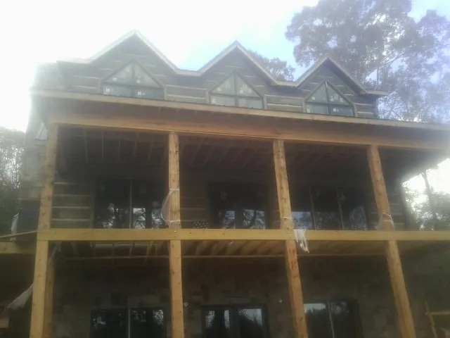 Dormers and porch framing on a large log home under construction — Roof Coating work by our crew in Cresco