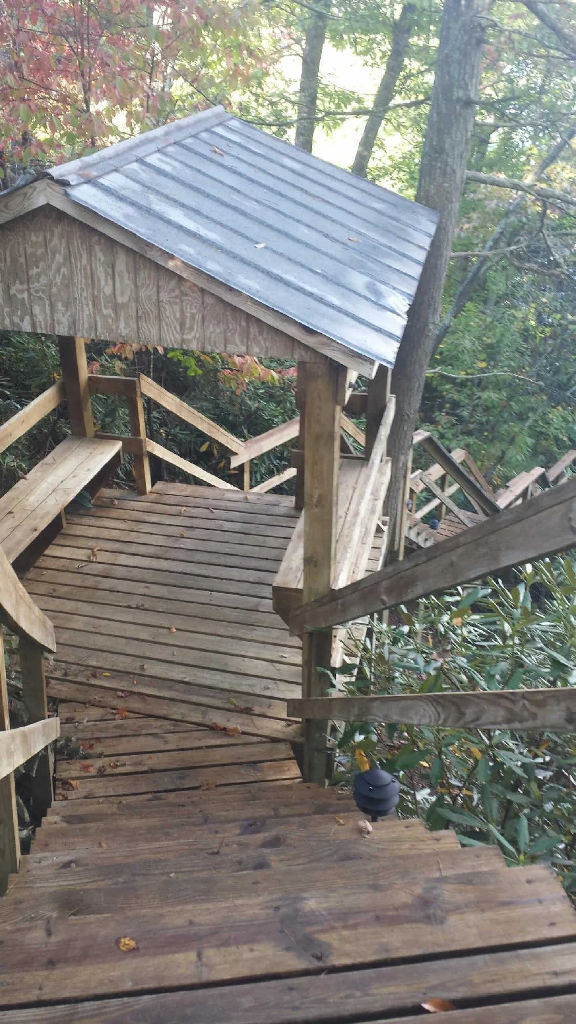 Metal roofed shelter over wooden steps on a wooded walkway — Skylight Repair & Installation work by our crew in Cresco